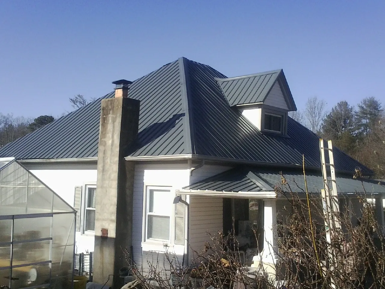 Dark blue standing seam metal roof on a white farmhouse with dormer — Slate & Tile Roof Repair by Roofing Brothers in Potts Camp