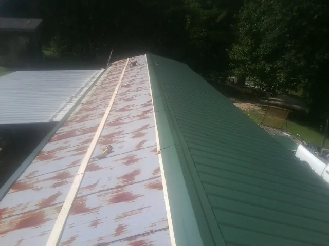 Old rusted panels beside newly installed green metal roofing — Wind Damage Roof Repair by Roofing Brothers in Potts Camp