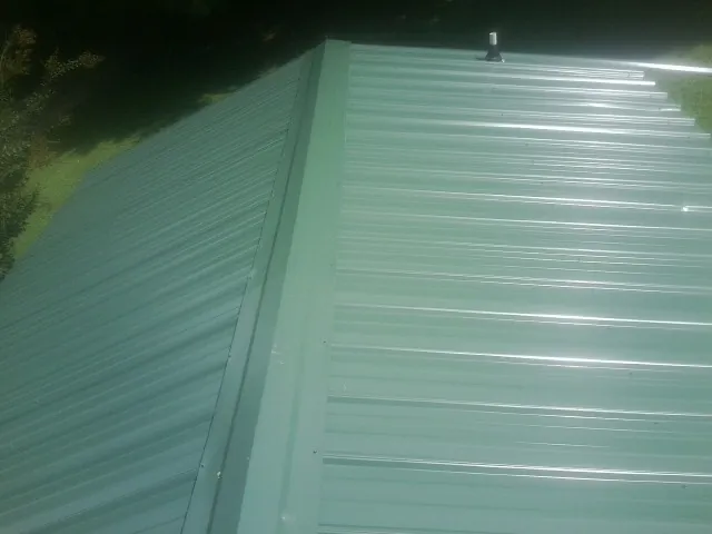 New green metal panels meeting at the ridge of a roof — Flat Roof Repair work by our crew in Potts Camp
