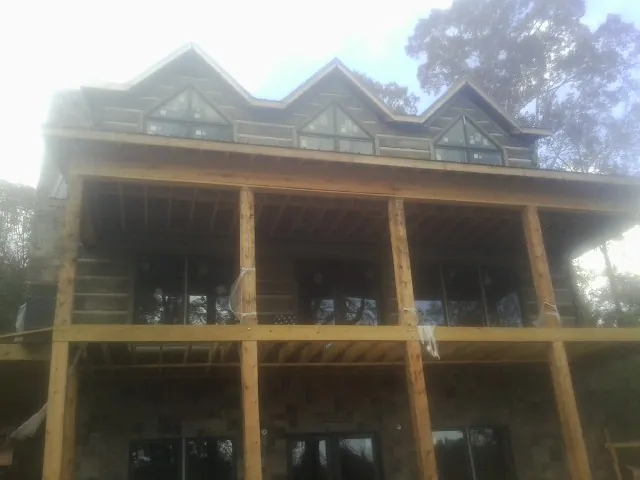 Dormers and porch framing on a large log home under construction — Roof Coating work by our crew in Potts Camp