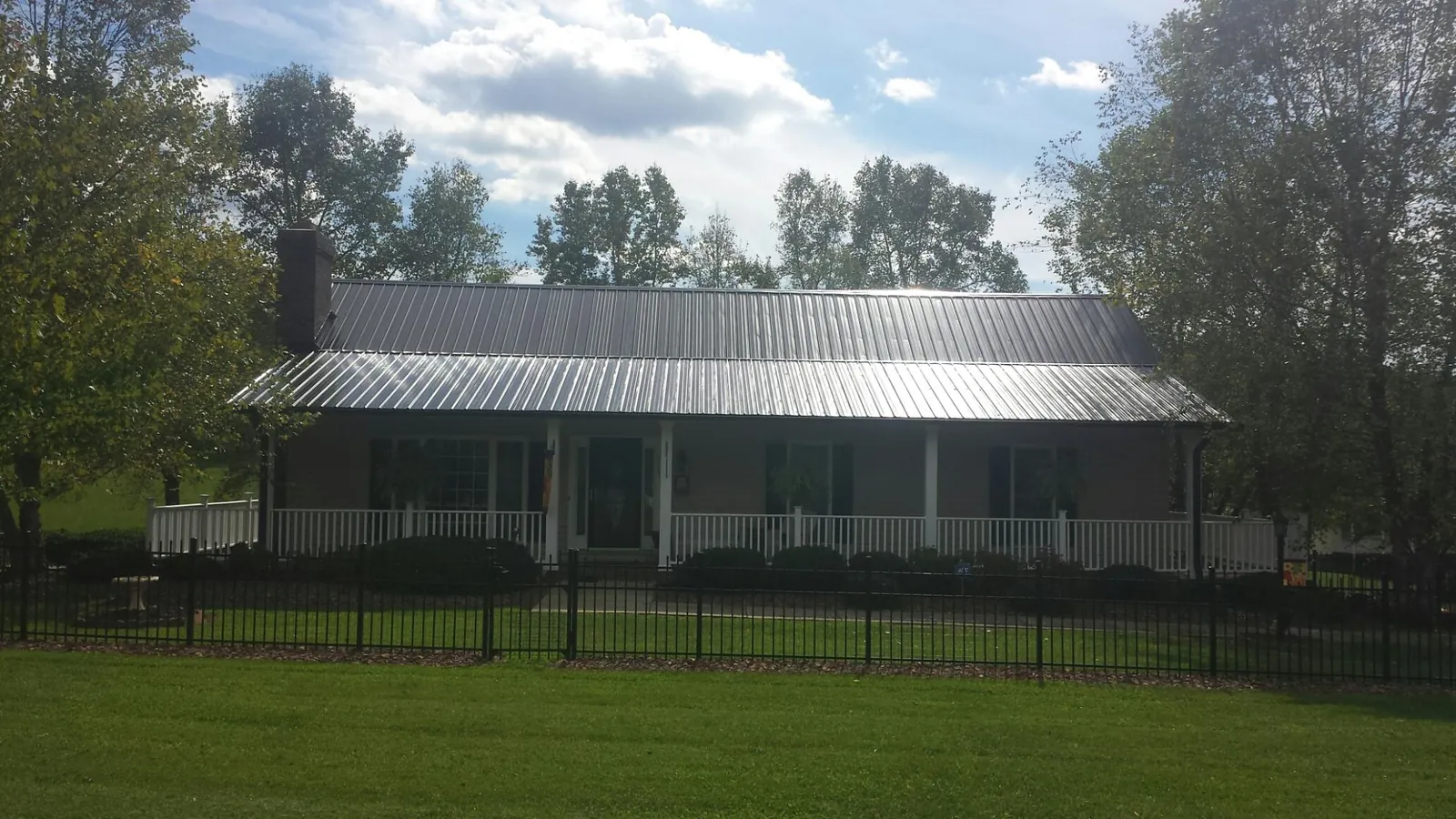 Gray metal roof on a brick ranch with a full width front porch — Gutter Guard Installation work by our crew in Potts Camp
