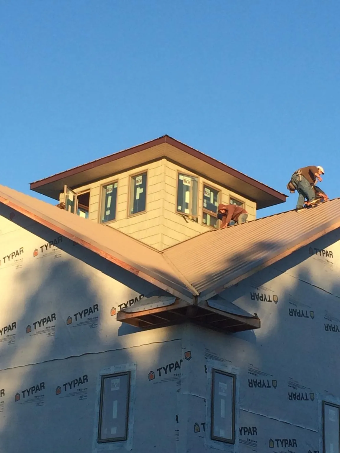 Roofers working around a rooftop cupola on a new metal roof at sunset — Roof Waterproofing in Potts Camp by Roofing Brothers